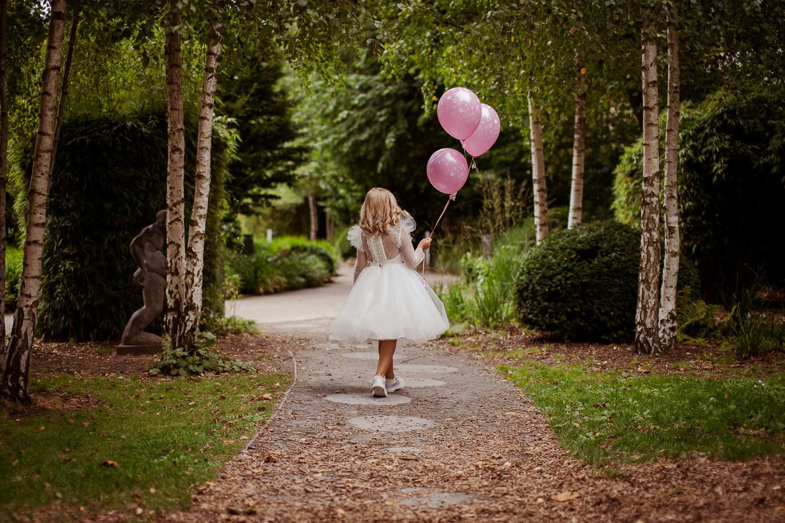 gilr in white dress and baloons in park